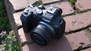 Canon R7 camera with RF-S 10-18mm lens attached sitting on a brick wall