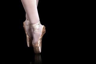Ballerina's feet on black background.