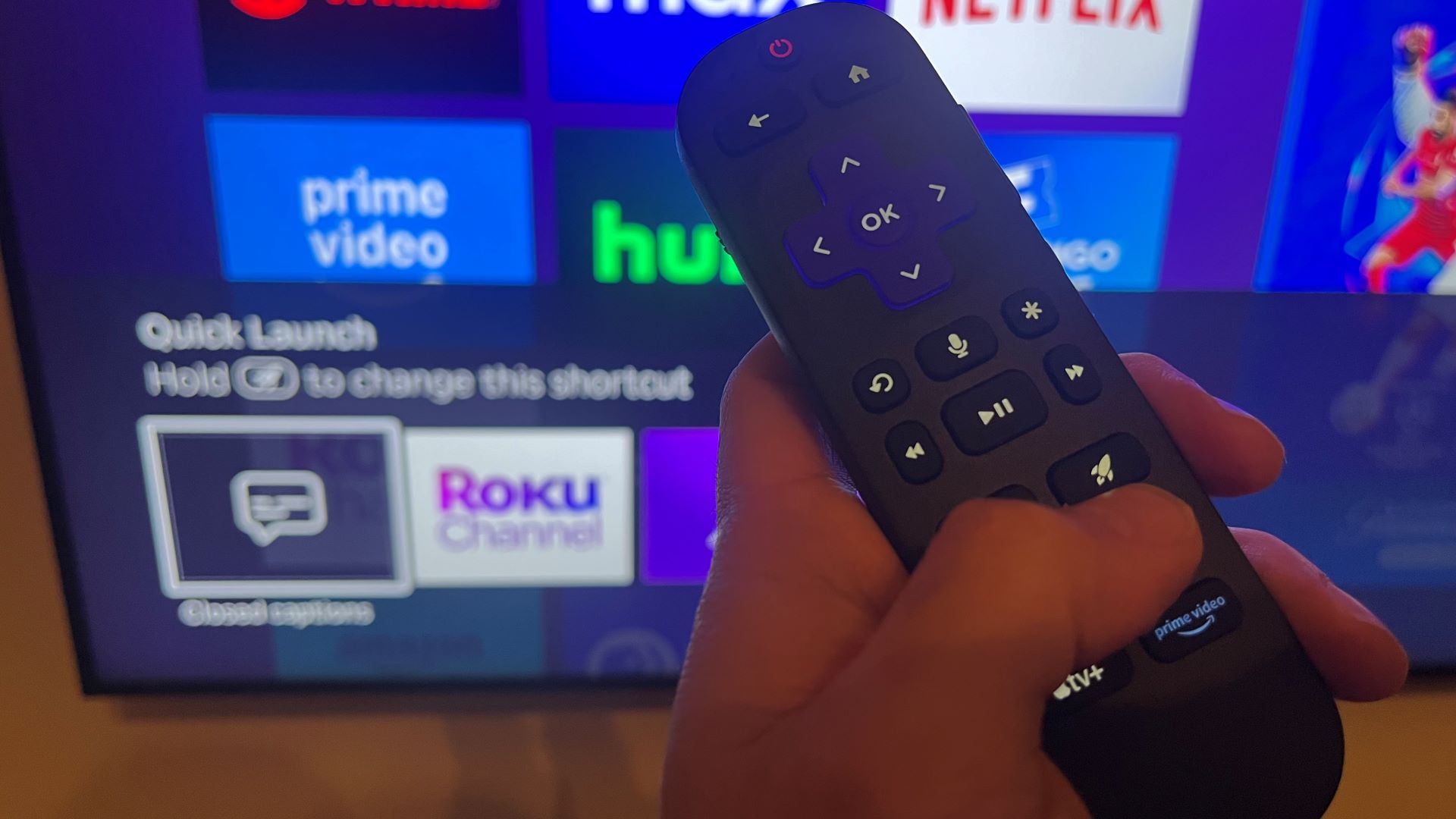 Roku Ultra (2024) remote held in hand with TV in background