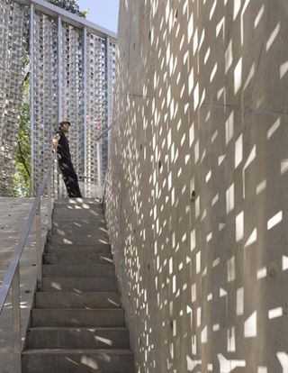 Concrete stairs next to concrete wall and metal screen