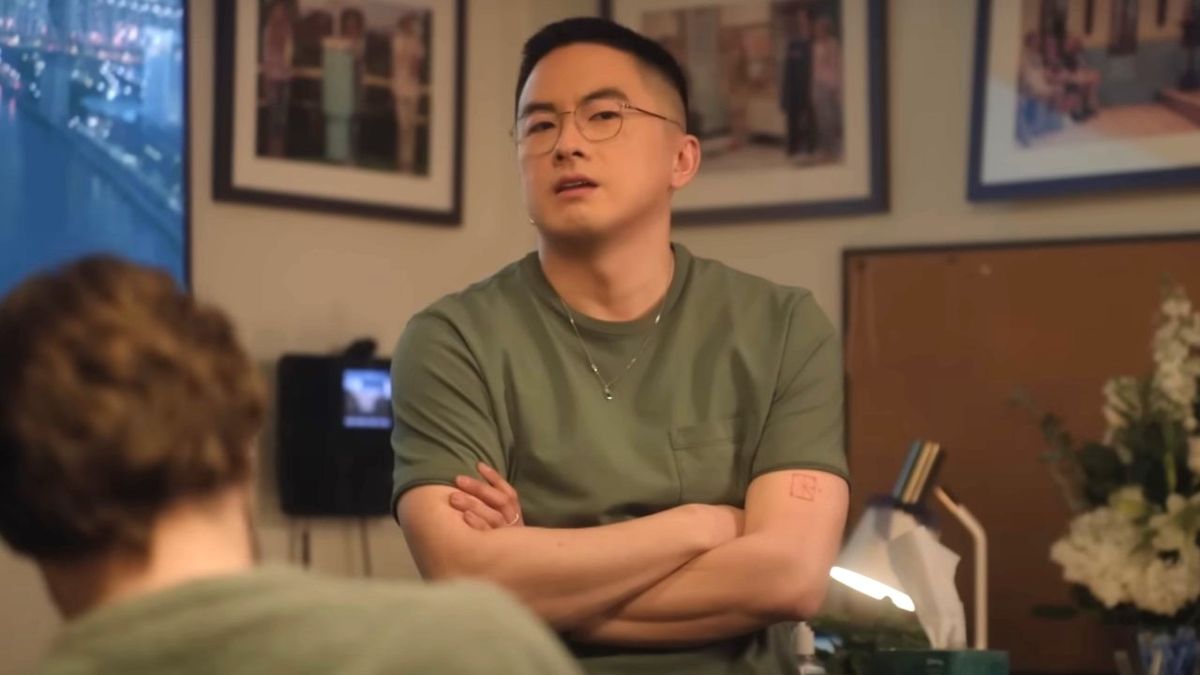 Bowen Yang stands with his arms crossed during a Saturday Night Live sketch.