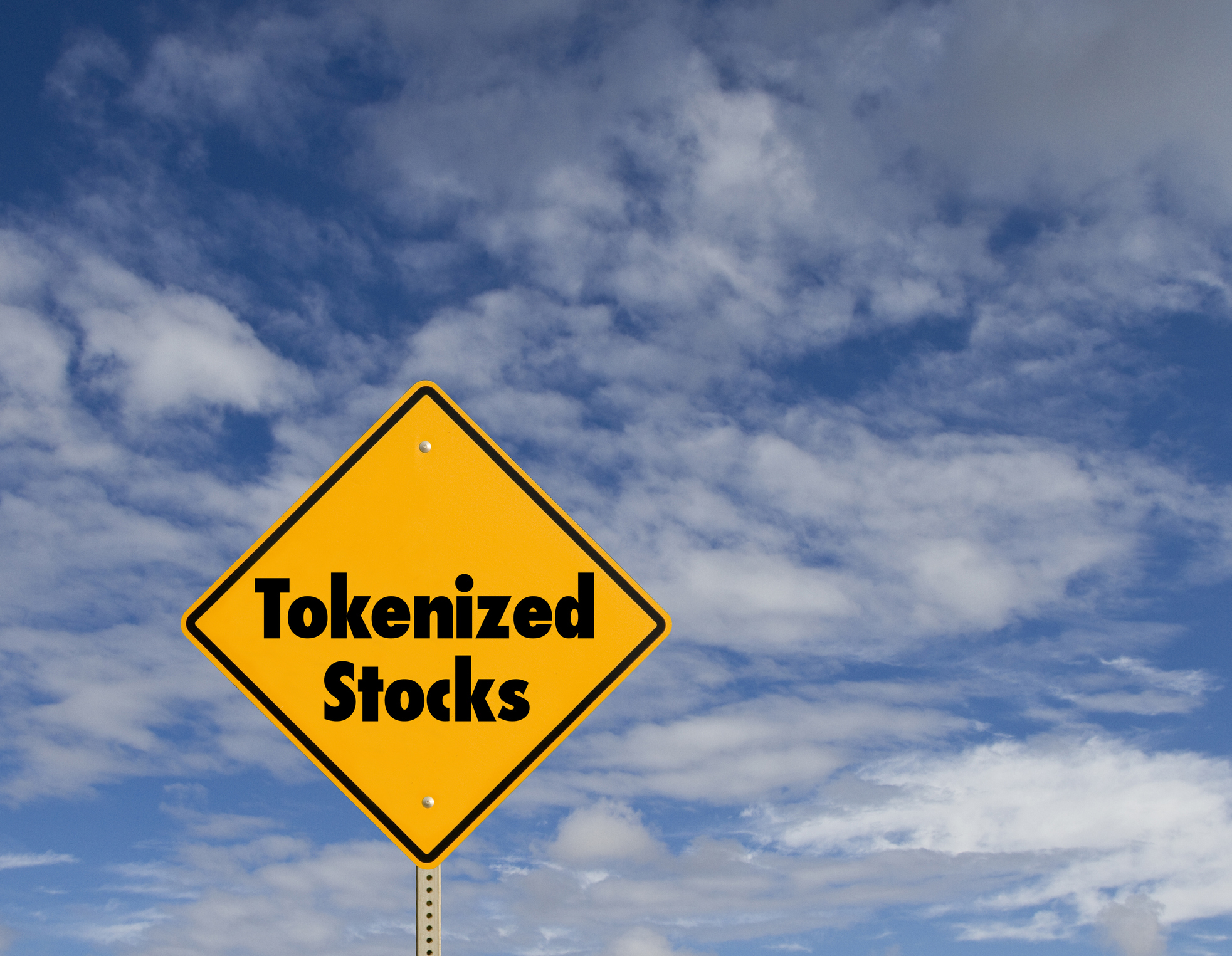 tokenized stocks written on a yellow street sign with a cloudy sky behind it