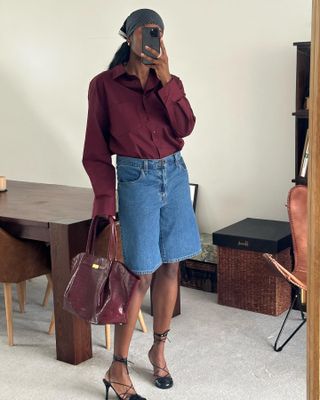 Woman in long denim shorts and burgundy accessories.