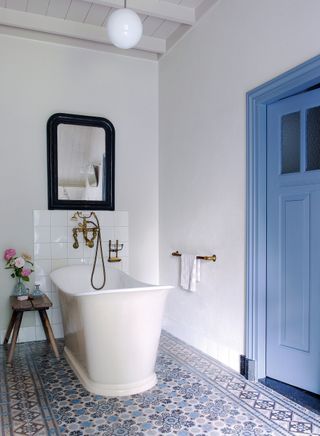 Blue room design ideas in a white scheme bathroom with a pop of blue and freestanding bath and patterned tiled floor