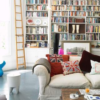 living room with wooden flooring and bookshelves and sofa with cushions