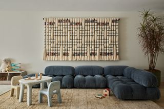 Play room and living area with a large wall tapestry and tufted blue sofa