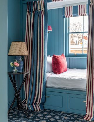 Blue bedroom with built in bed and blue walls with red accents
