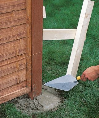 smoothing down concrete filling around a fence post hole