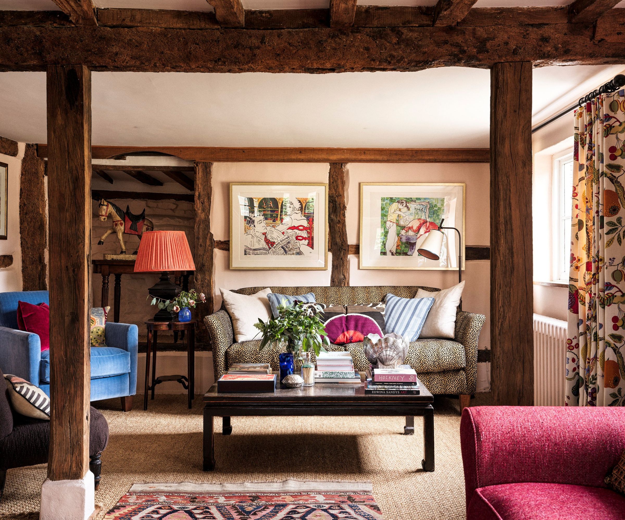 Cozy living room with wooden beams and a leopard print couch and blue armchair, a low black coffee table sits between
