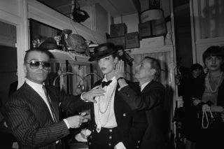 German fashion designer Karl Lagerfeld (L) and French hairdresser Alexandre de Paris (R) prepare a model backstage ahead of the presentation of spring-summer haute couture collection for Chanel, on January 24, 1983