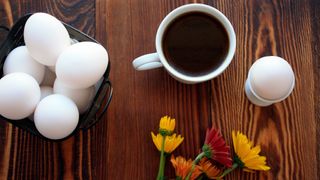 Cup of coffee with eggs on table
