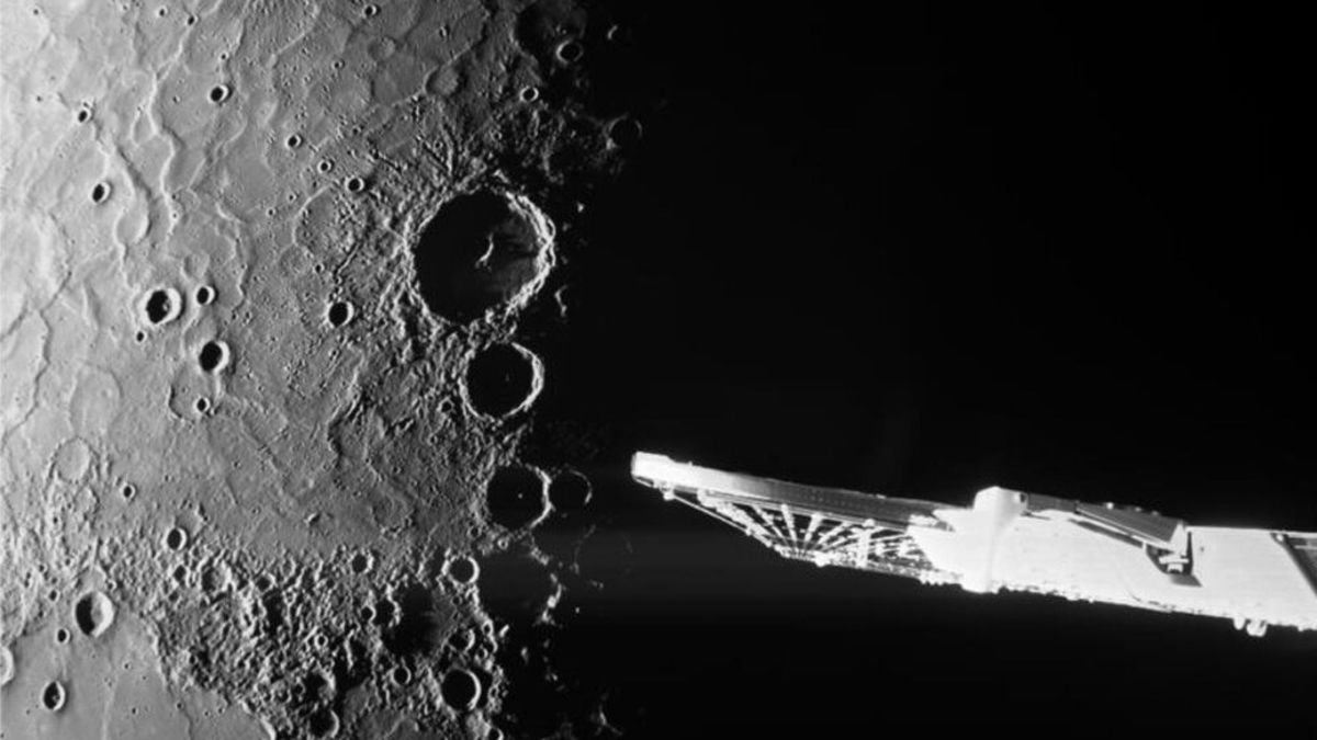 Deep craters seen on a planet in this black and white image. A solar wing is visible on the right side.
