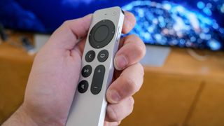 The Apple TV 4K (2022) remote in hand, tilted to the side