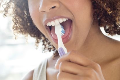 Should you brush your tongue: image of woman brushing tongue