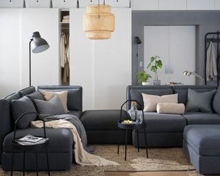 A grey modular sofa in a small studio apartment with coat rail in background