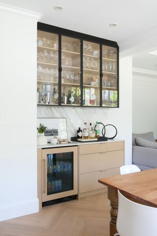 A kitchen with a large glass cabinet and a wooden dresser for bar accessories