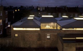 An aerial view of the roofs of the residential home with the lights on n all the visible rooms
