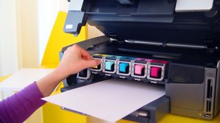 A hand changing the ink cartridge on an open printer
