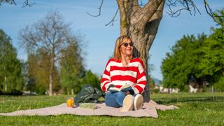 Woman sitting on yoga mat under tree in the park