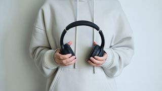 a person holding a pair of black wireless over-ear headphones