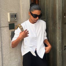 audrey wears white cardigan, black pants, black slingbacks and a green handabg