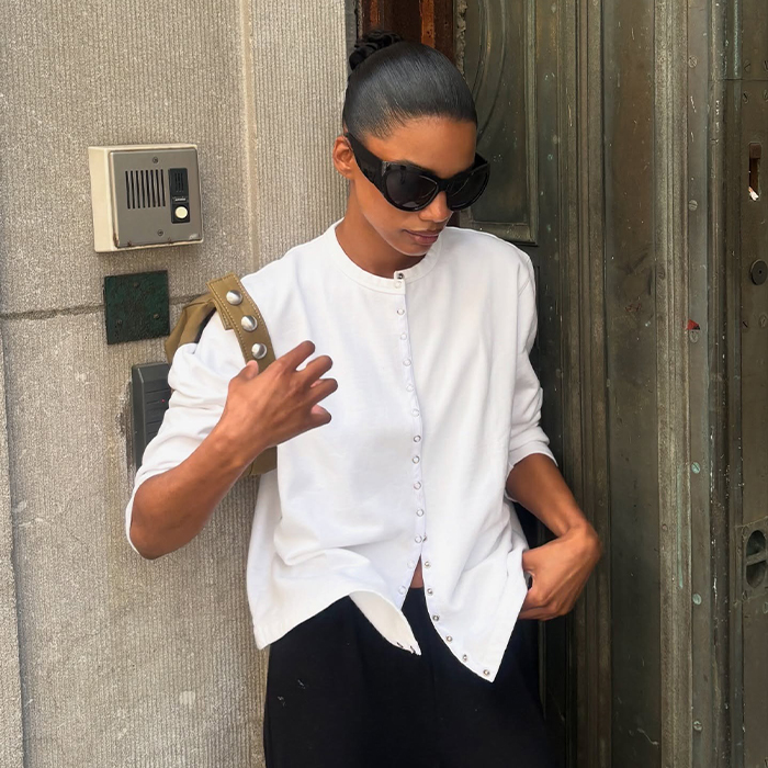 audrey wears white cardigan, black pants, black slingbacks and a green handabg