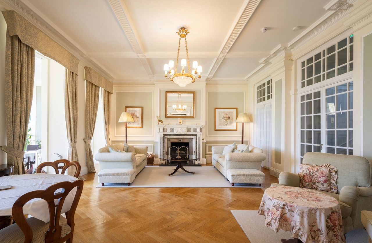 The living room is brightly lit form the large windows and has an old fashioned fireplace
