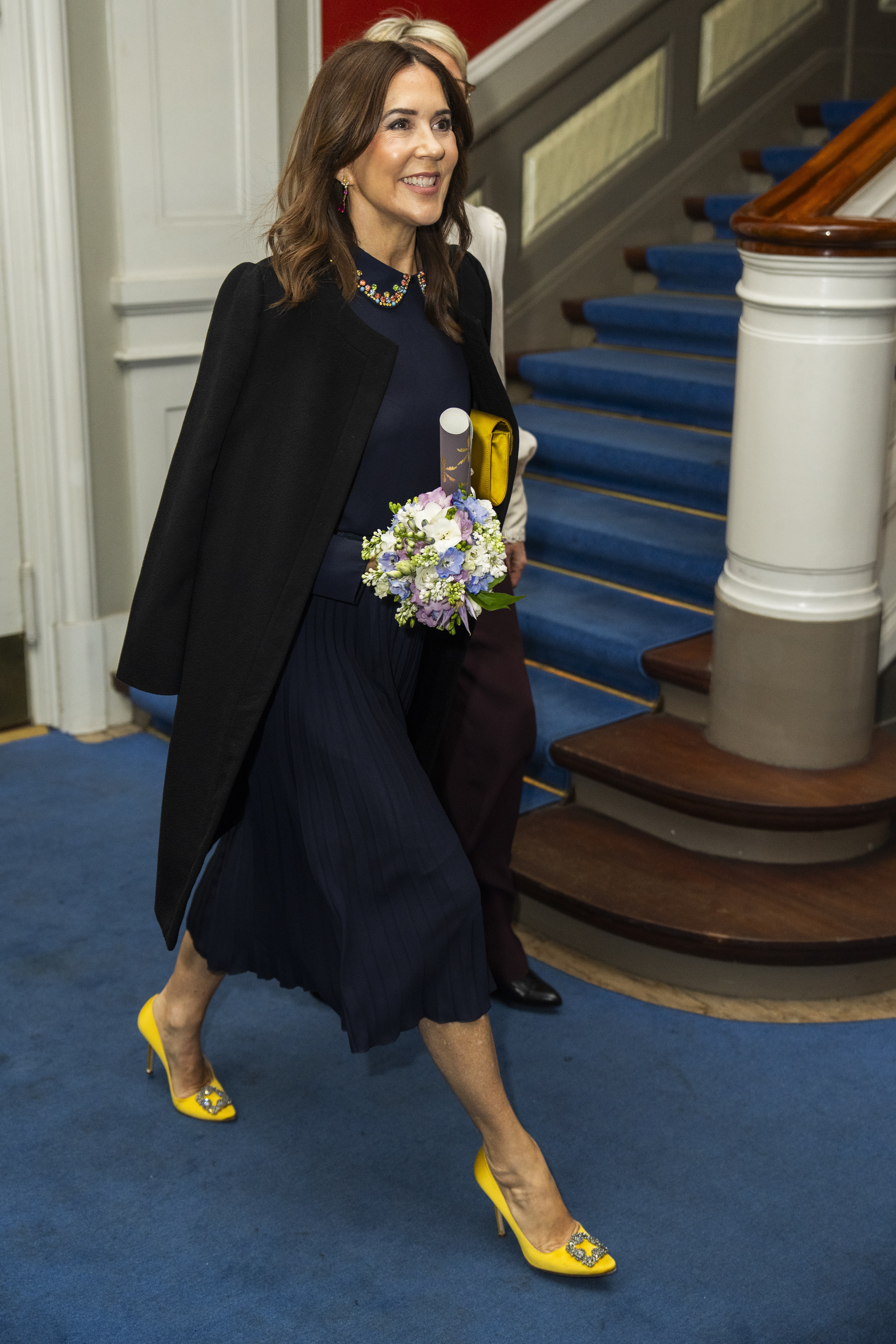 Queen Mary of Denmark walkig in a navy outfit and yellow heels