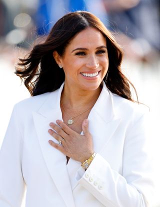 Meghan Markle in a white blazer, showing off her enagagement ring