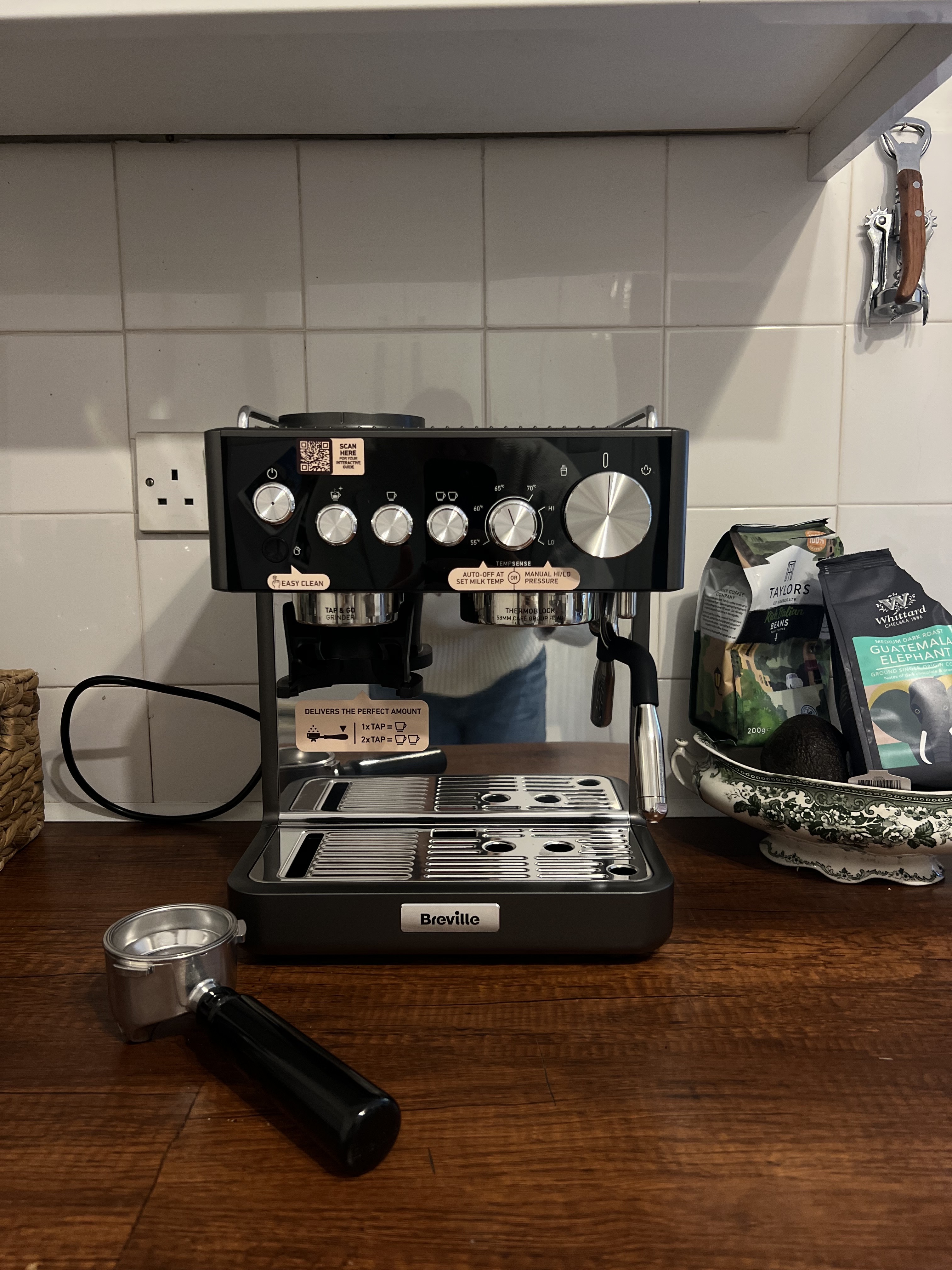 Image of the Breville Barista Sense Espresso Machine in black and gray sitting on a wooden countertop in front of a white tile backsplash.