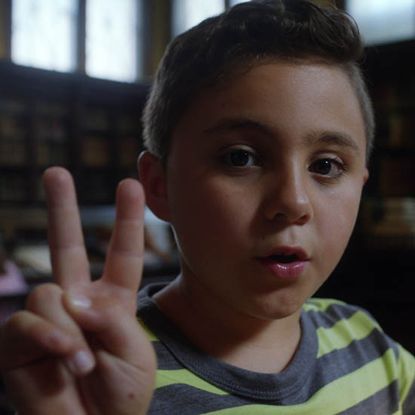 young boy with stropped t shirt and victory sign