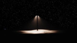 An artist&#039;s rendering of a streetlamp on a dark landscape with stars behind it