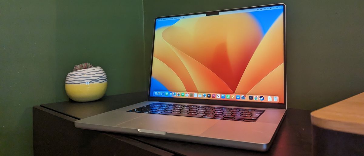 MacBook Pro 16-inch (2023) on wooden desk with green background