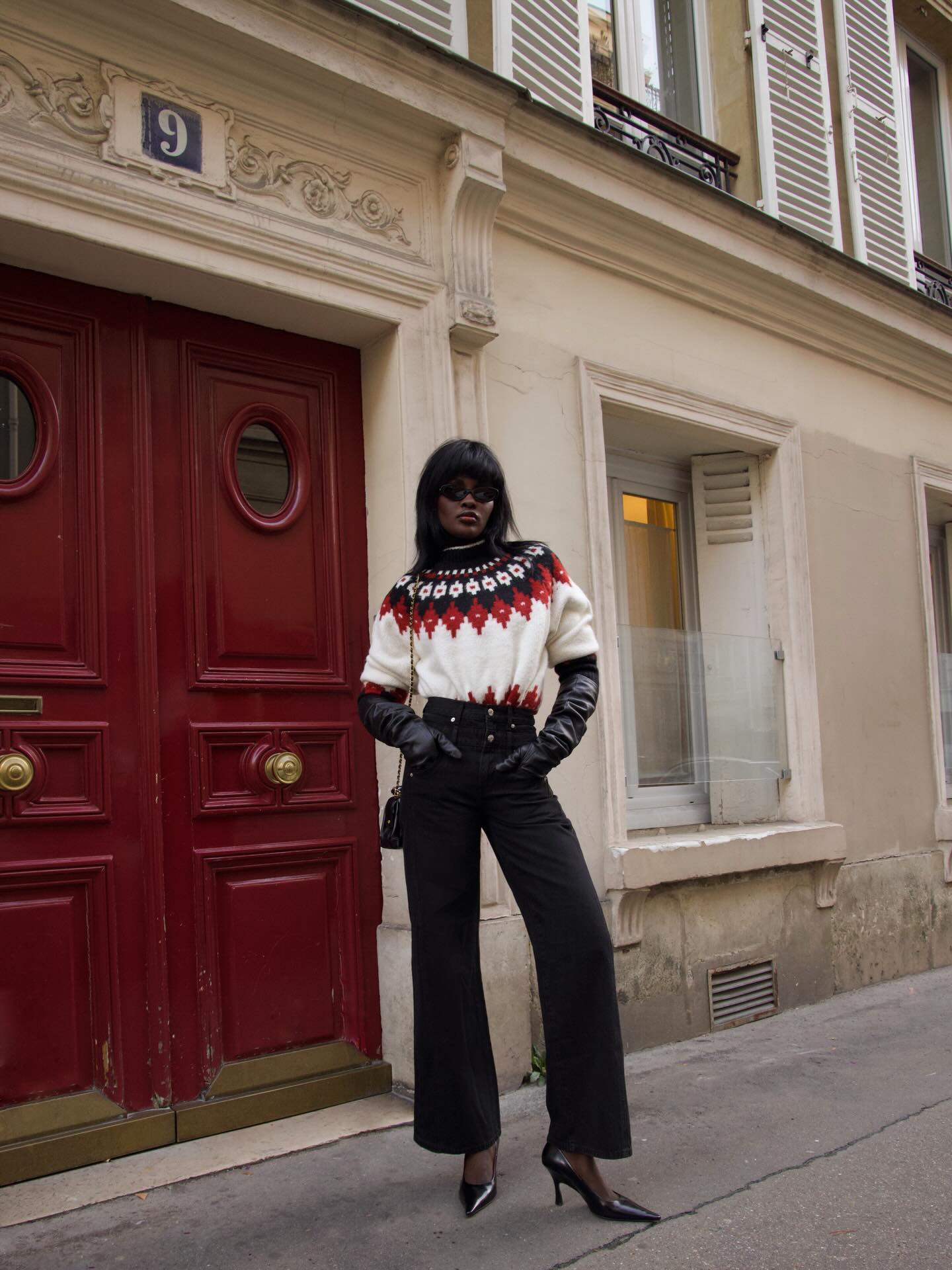 An image of an influencer in a red, white and black fair isle sweater, leather gloves, black wide-leg trousers and black high heels
