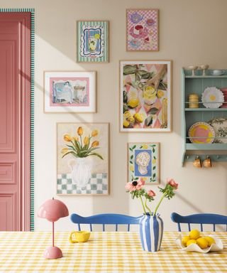 Six colorful wall art prints, a pink door, a mint green wall shelf, a yellow checked dining table with a pink lamp, a blue and white striped vase with flowers, a lemon plate, Dining area with blue chairs