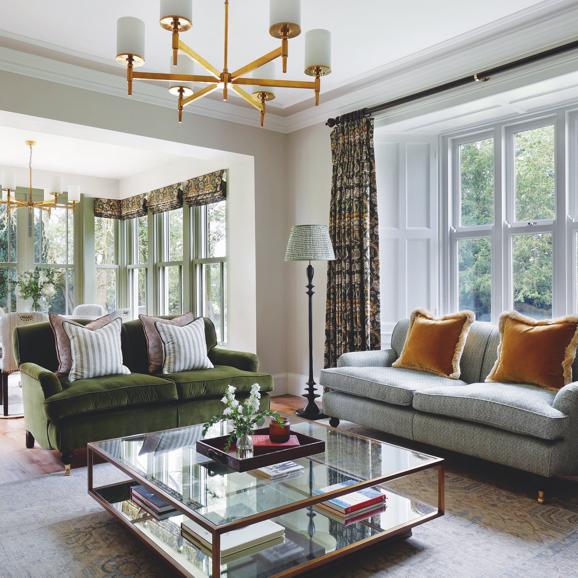 large living room with two sofas around glass coffee table with brass chandelier above