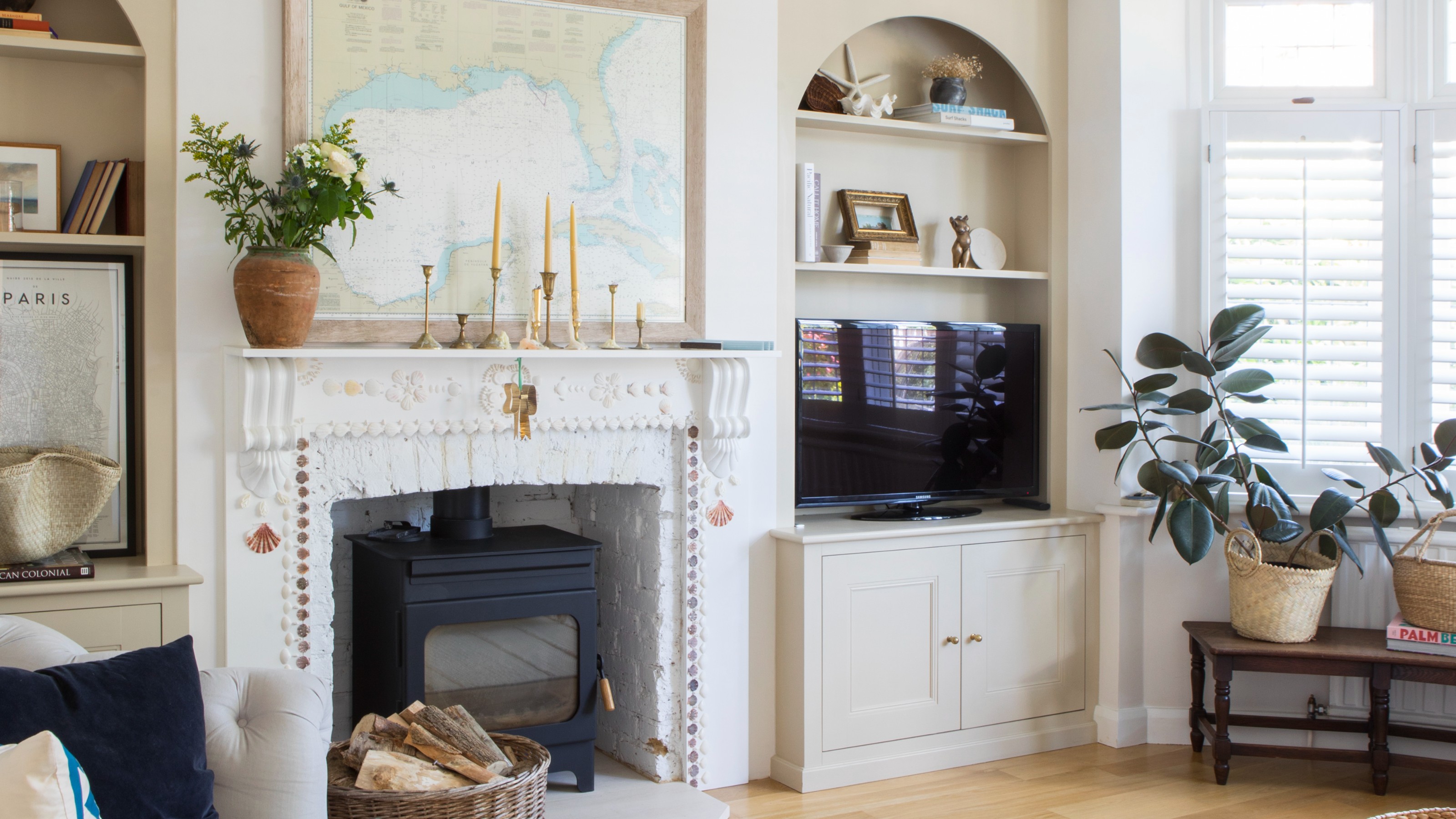 A cream-painted living room with arched alcoves with one of them featuring a TV