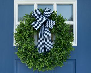 Artificial Boxwood Wreath with a blue and white striped ribbon on a blue and white exterior door