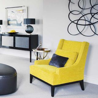 living room with white wall and carpet flooring with yellow armchair