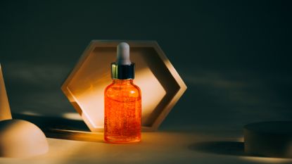 Bright orange bottle of royal jelly face oil placed near a set of shapes 