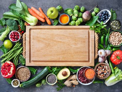 Wooden Cutting Board Surrounded By Fruits And Vegetables