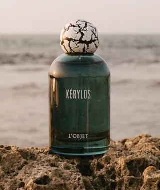 a bottle of l'objet perfume in front of the sea