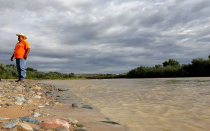 A man stands along the contaminated San Juan River.
