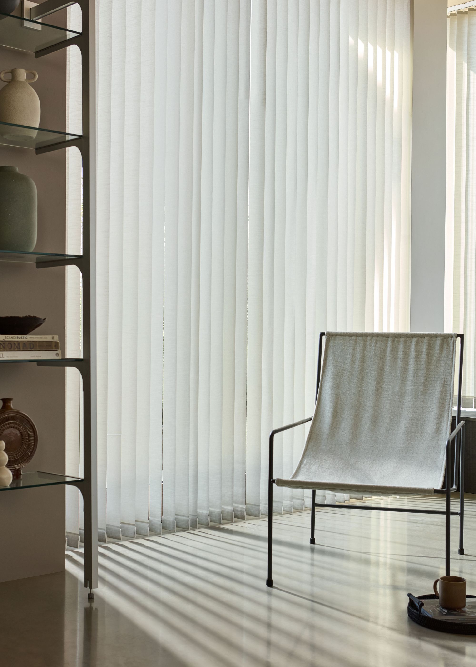 corner of modern living space with white vertical blinds and minimalist armchair with metal frame