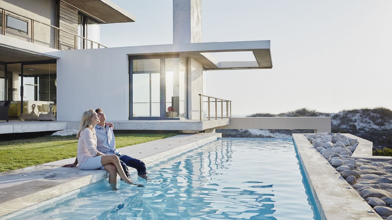 A wealthy couple sits by a pool with their favorite long-term investment.