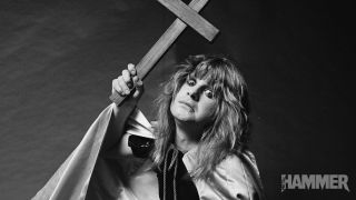 A black-and-white photo of Ozzy Osbourne holding a large wooden cross