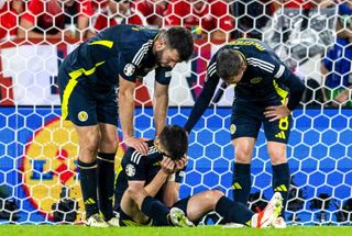 Scotland's Kieran Tierney is colsoled by Grant Hanley and Callum McGregor after going down injured during a 2024 UEFA European Football Championship Group A match between Scotland and Switzerland at the Cologne Stadium, on June 19, 2024, in Cologne, Germany