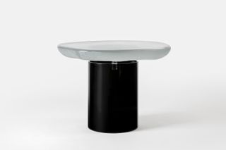 A side table made of white glass top and black base.