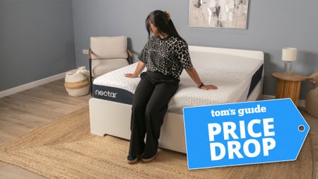 A woman sitting on the end of the Nectar Classic mattress in a bedroom, with a Tom's Guide 'PRICE DROP' badge overlaid