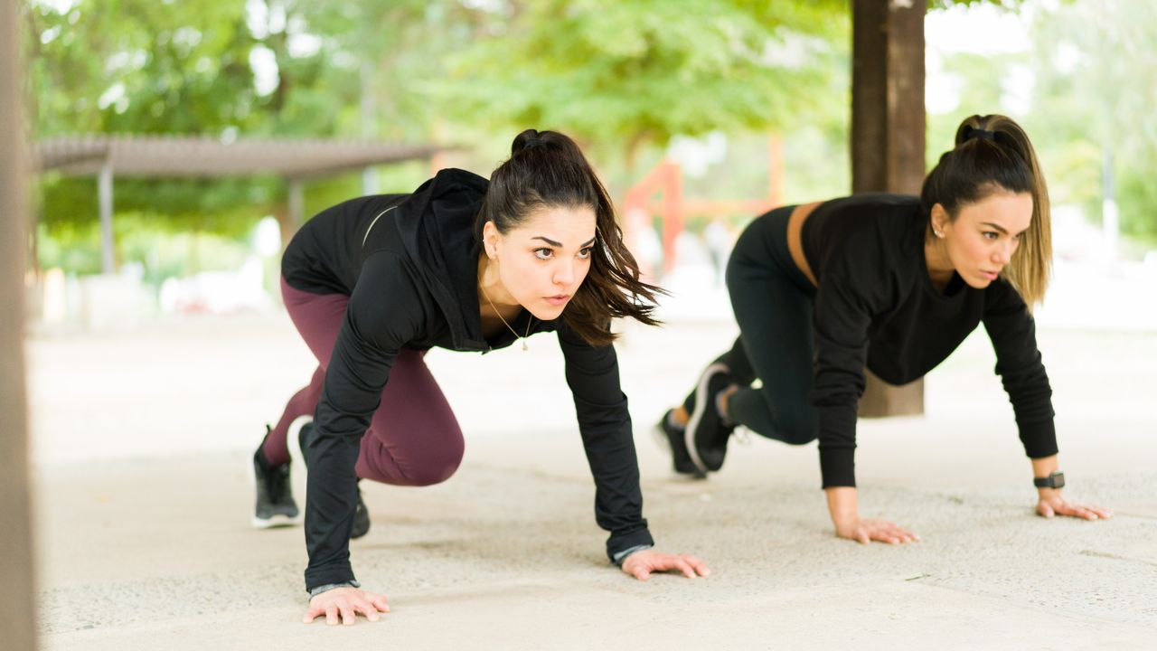 Two women doing mountain climber exercises outside